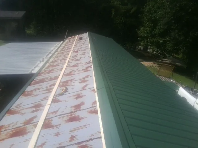 Old rusted panels beside newly installed green metal roofing — Wind Damage Roof Repair by Roofing Brothers in Port Arthur