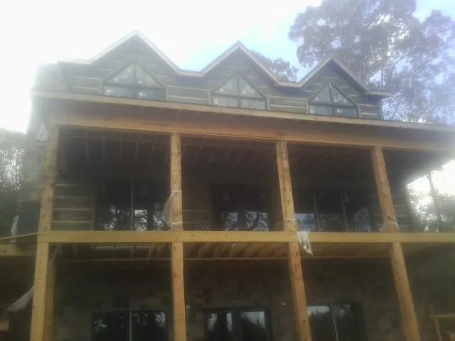 Dormers and porch framing on a large log home under construction — Roof Coating work by our crew in Port Arthur