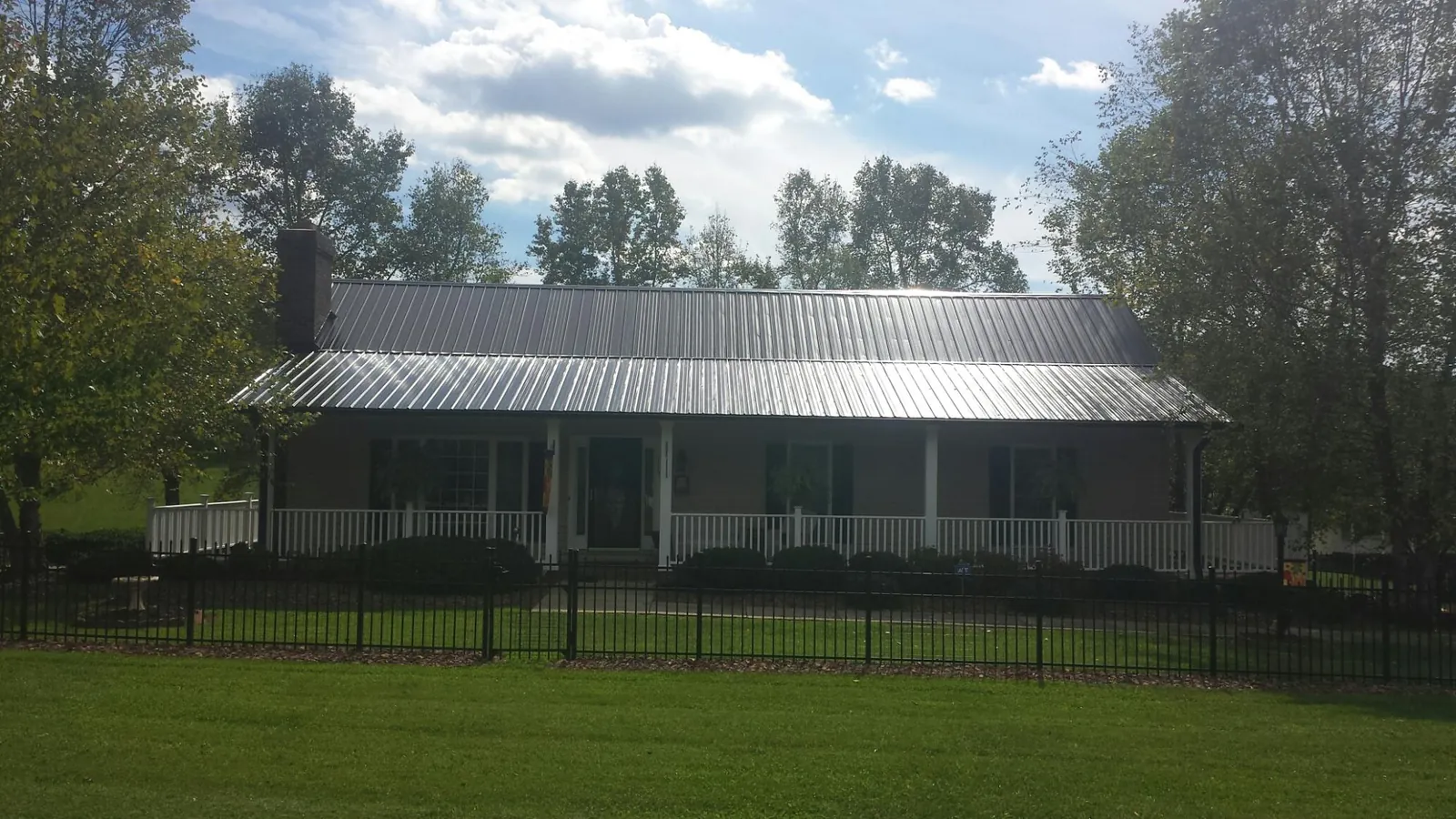 Gray metal roof on a brick ranch with a full width front porch — Gutter Guard Installation work by our crew in Port Arthur