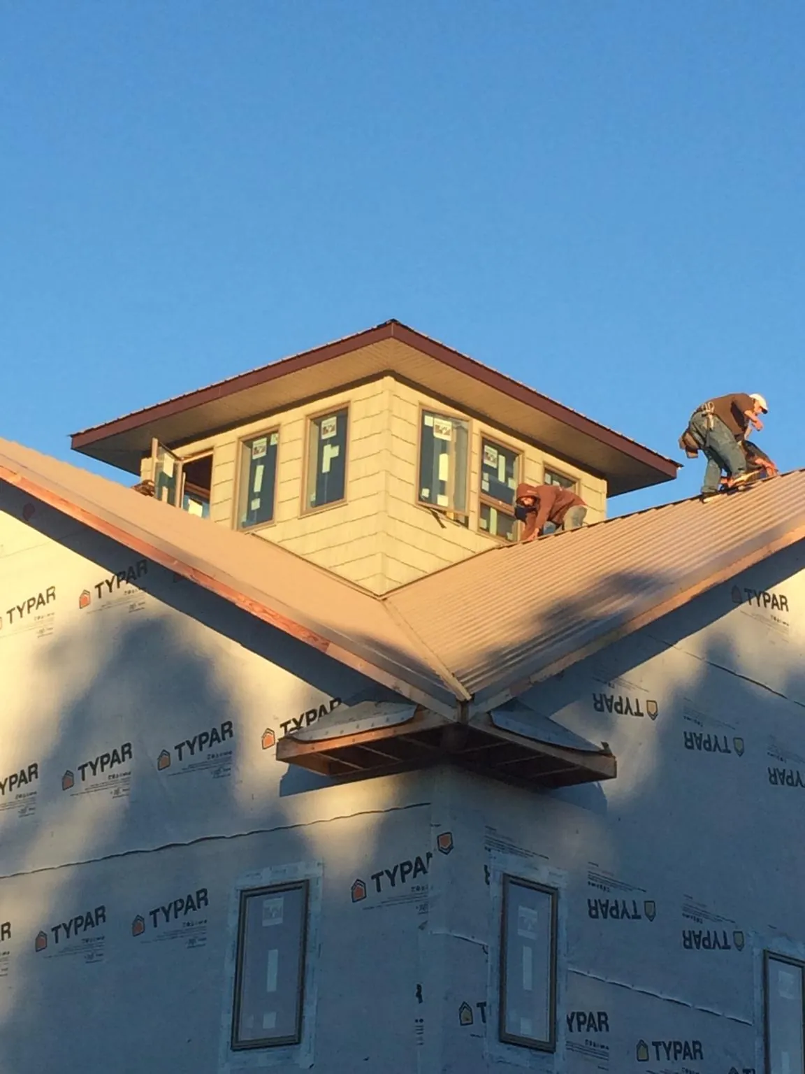 Roofers working around a rooftop cupola on a new metal roof at sunset — Roof Waterproofing in Port Arthur by Roofing Brothers